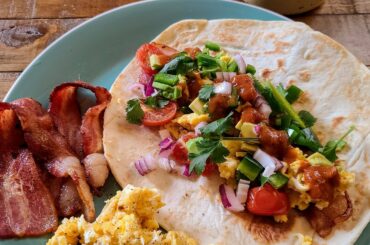 Breakfast burrito with scrambled eggs, thick cut sweet and spicy bacon, avocado, jalapeno, cilantro, seared cherry tomatoes, and Secret Aardvark hot sauce.