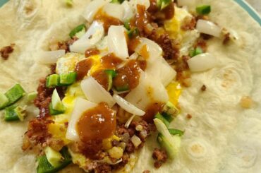 Breakfast burrito with eggs over easy, corned beef hash, diced jalapenos, sauteed onions, and Secret Aardvark hot sauce.