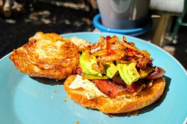 Breakfast croissant with an over easy egg, sweet and spicy bacon, homegrown heirloom tomatoes, avocado, and sauteed onions and Caribbean Red peppers (also homegrown).