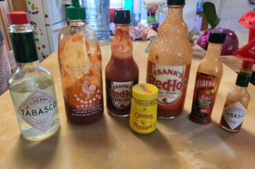 My refrigerator line up. The big Tabasco bottles make great vinegar dispensers. And the Colemans is there because it can be painfully great!.(hottest on the line Habenaro dollar store for the win.