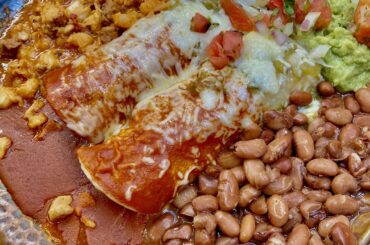 Christmas style chicken enchiladas with pozole, pinto beans, salad, guacamole and crema (sour cream)