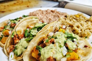 Chicken al pastor tacos with rice and beans.