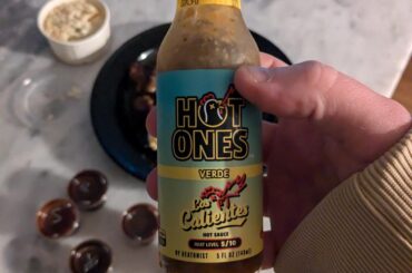 Another hand holding a bottle of sauce