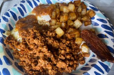 Desayuno servido, chorizo, tocino, patatas y huevos y salsa roja