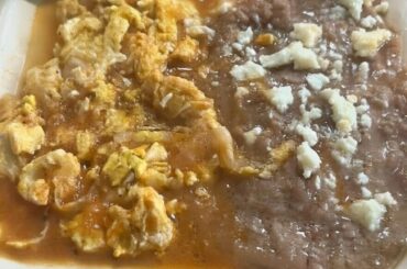 Huevos con salsa roja con frijoles refritos y queso fresco con tortillas de harina