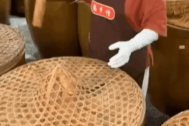 This woman opening a barrel of fermenting peppers, with a garlic topping.