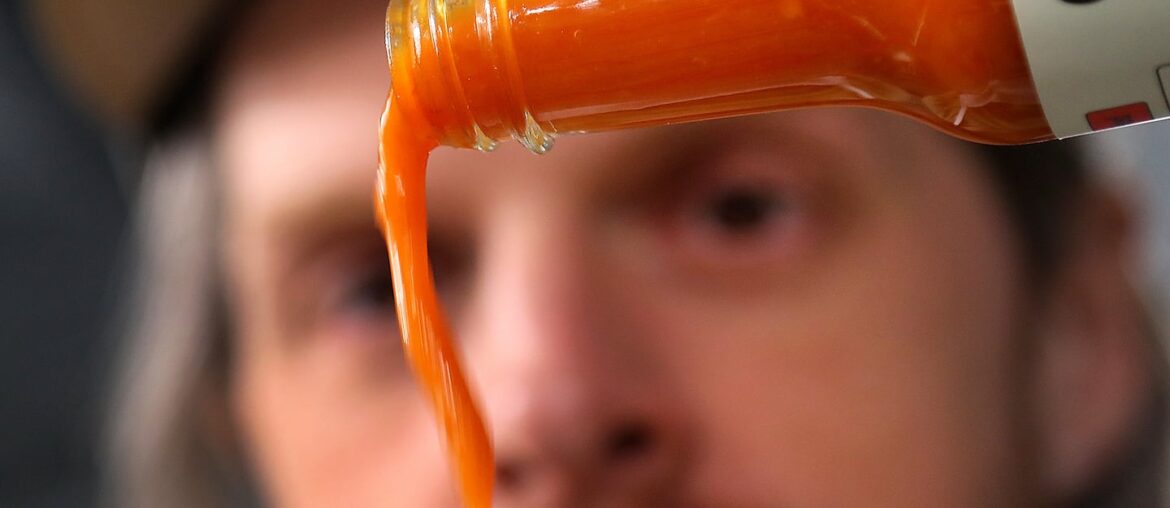 Founder Brian Ruhlmann pours a bottle of Mill City Red, one of Craic Sauce's hot sauces.