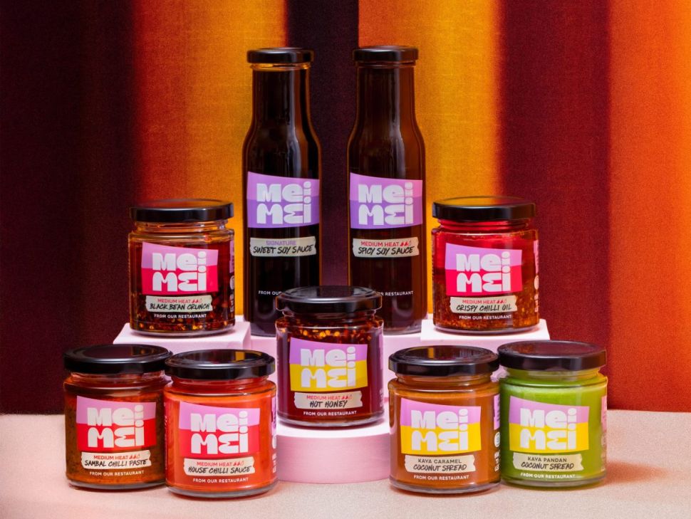 Colorfully labeled of Mei Mei hot sauces stacked in a pyramid structure on table.