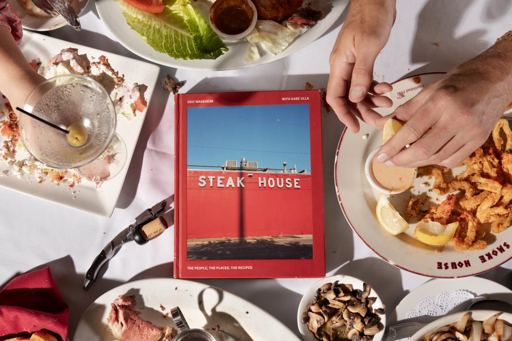 Eric Wareheim's new cookbook, "Steak House," surrounded by a classic spread from Smoke House.
