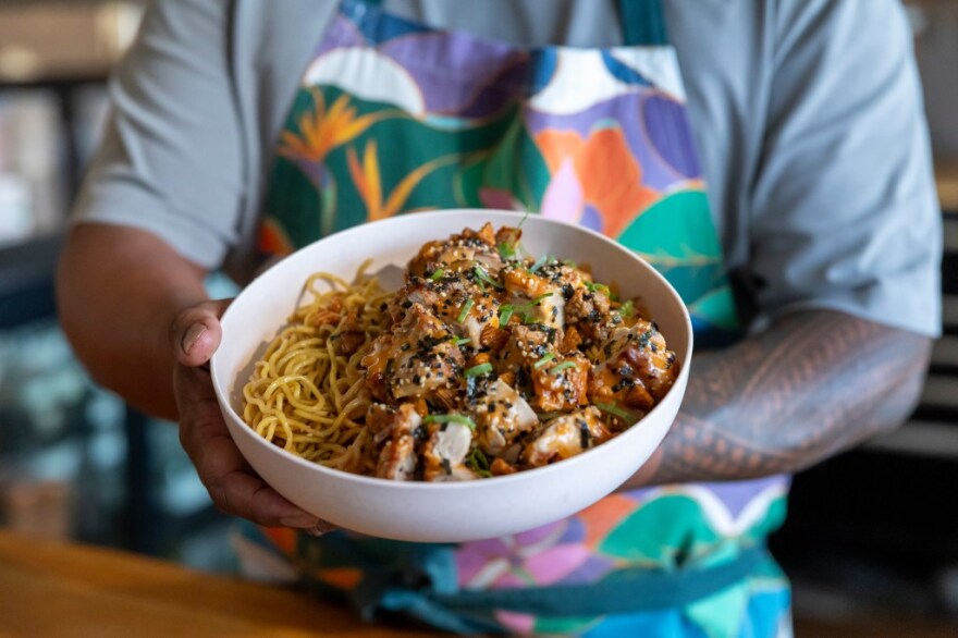 Chef Sheldon Simeon holding his dish featuring mochiko chicken and garlic noodles, which will be one of the meal options on board Hawaiian Airlines flights.