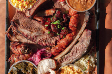 A tray of brisket, pineapple sausage, smoked turkey, corn salad, green chile mac and cheese, and more.