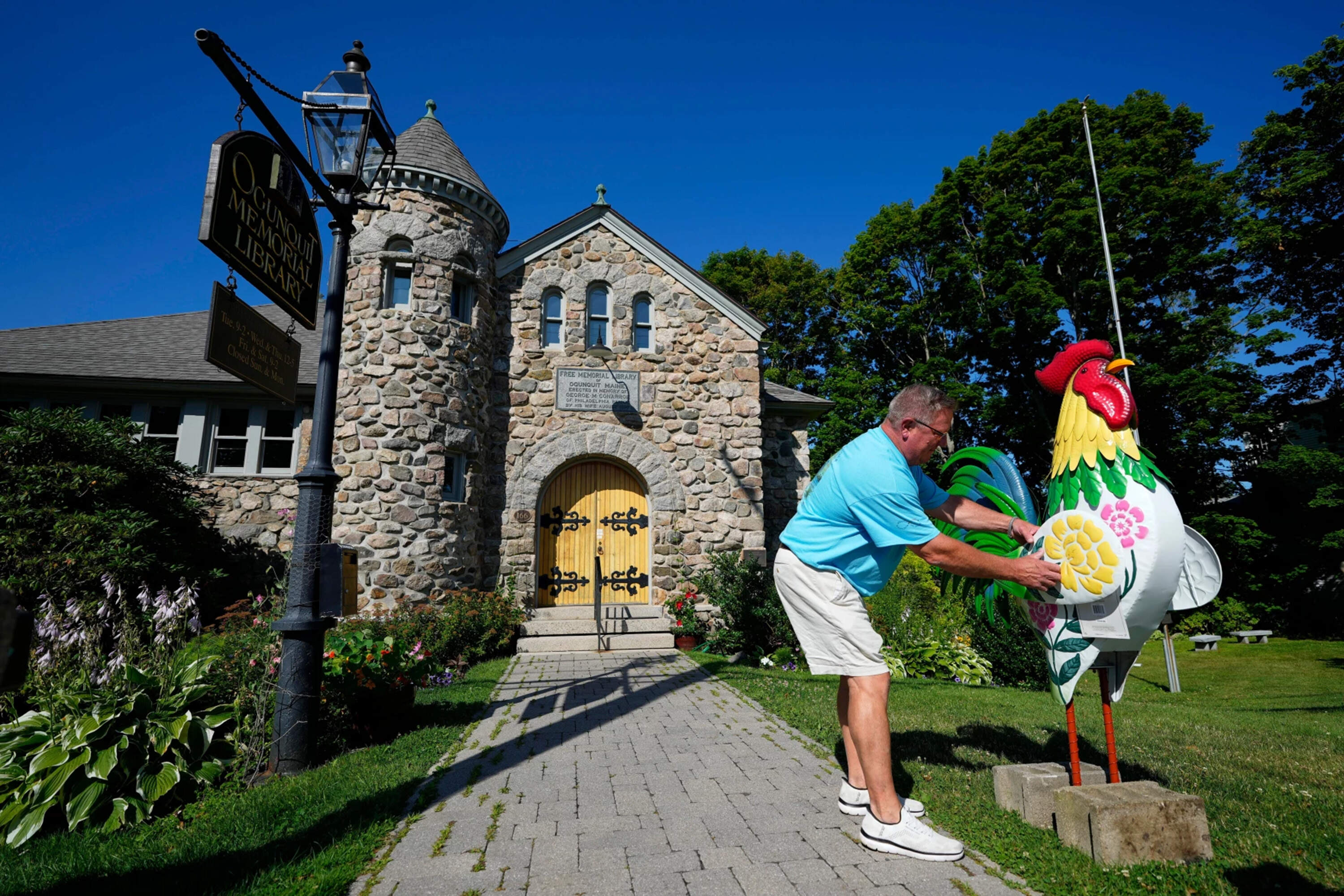 David LeBlanc sets up a rooster in front of the Memorial Library in Ogunquit, Maine on July 23. (Robert F. Bukaty/AP)