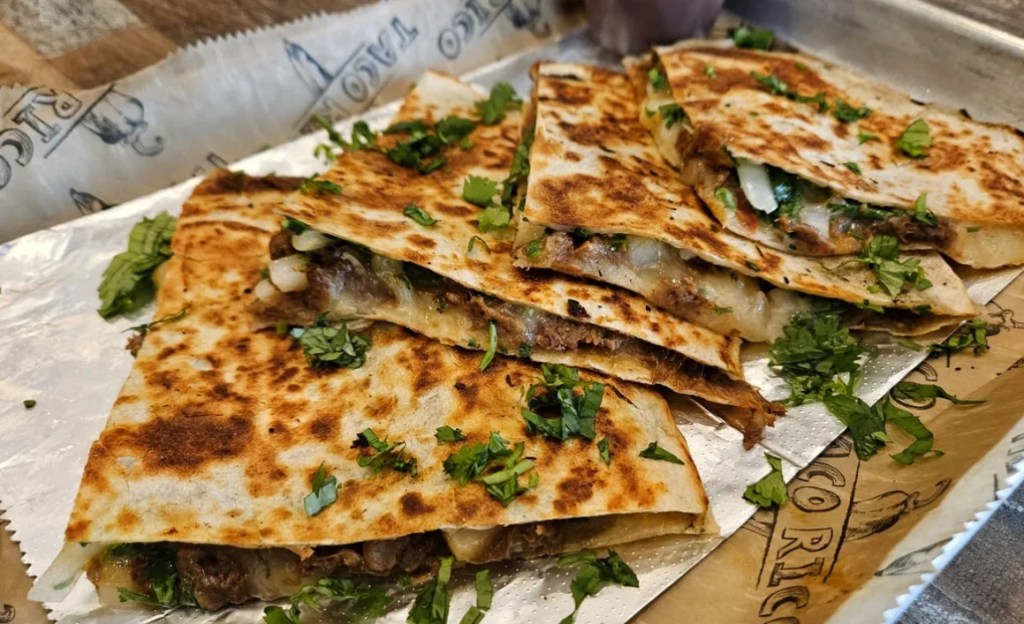 three quesadillas with toppings on a tray