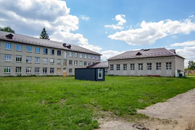 A three-story school structure surrounded by greenery and a clear sky. (stock photo via Pexels)