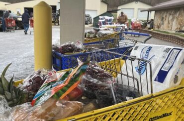 Shopping carts are filled with groceries while people go through them.