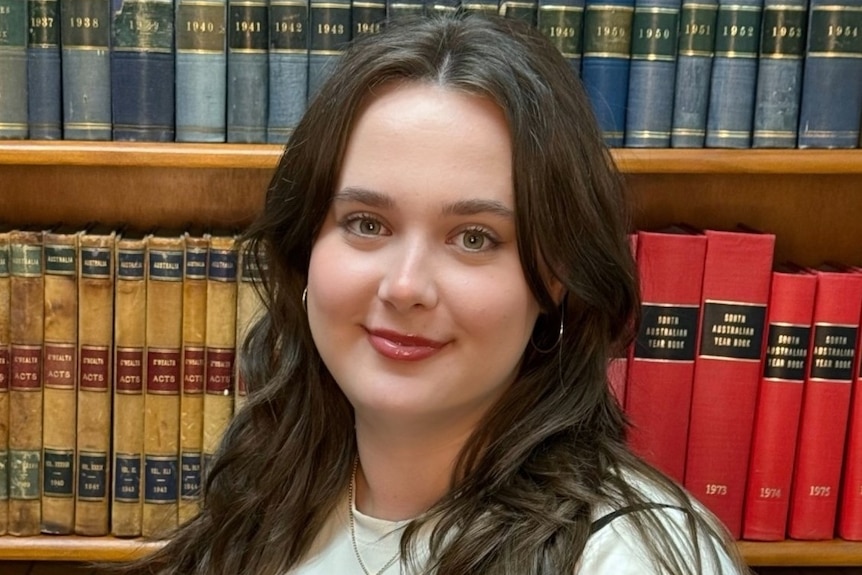 A woman with glasses on looks at the camera.