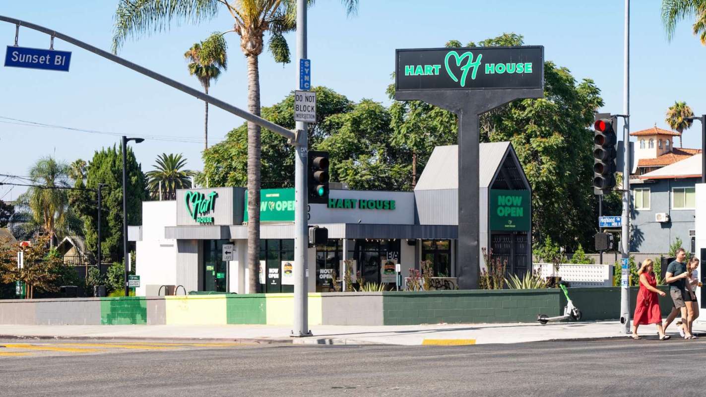 A restaurant building with a sign reading "Hart House" and palm trees nearby, located at an intersection.