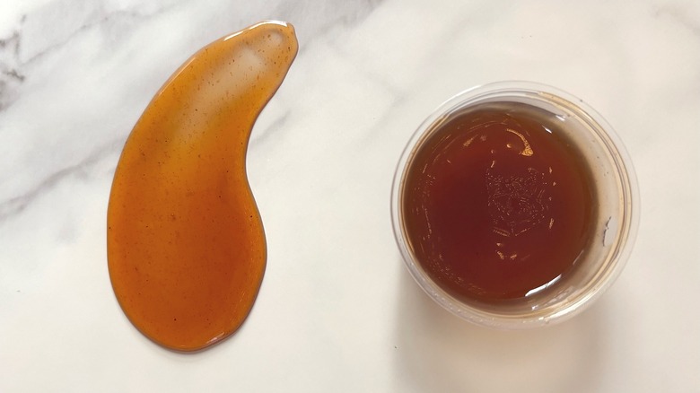 Small container and smear of Subway hot honey on marble surface
