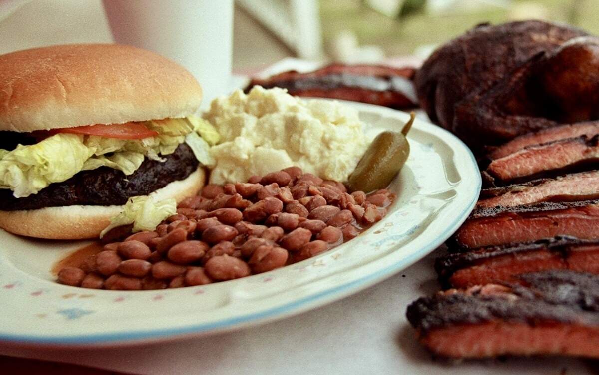 A smoked brisket burger with pinto beans and potato salad, plus a whole barbecued chicken and pork ribs at Longoria’s BBQ in Everman, Texas, as seen Nov. 22, 2000.