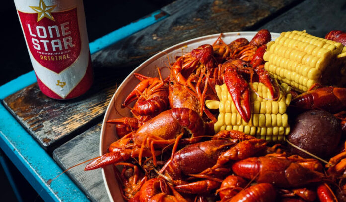 A plate of crawfish with corn and a bottle of Lone Star